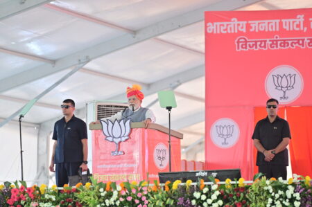 Hindistan Başbakanı Narendra Modi'nin BJP mitinginde konuşma yaptığı sahne; arka planda partinin lotus amblemi ve kalabalık destekçi grubu.